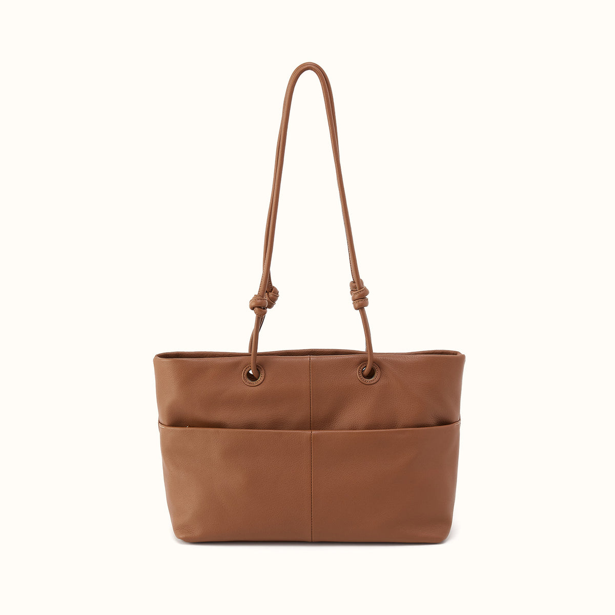 A medium brown leather tote bag with a single shoulder strap featuring knotted details at the top, set against a plain off-white background.