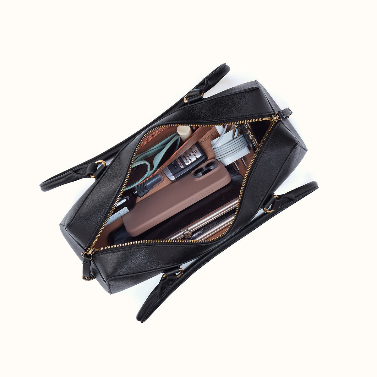 Black handbag with gold zippers open on a white background