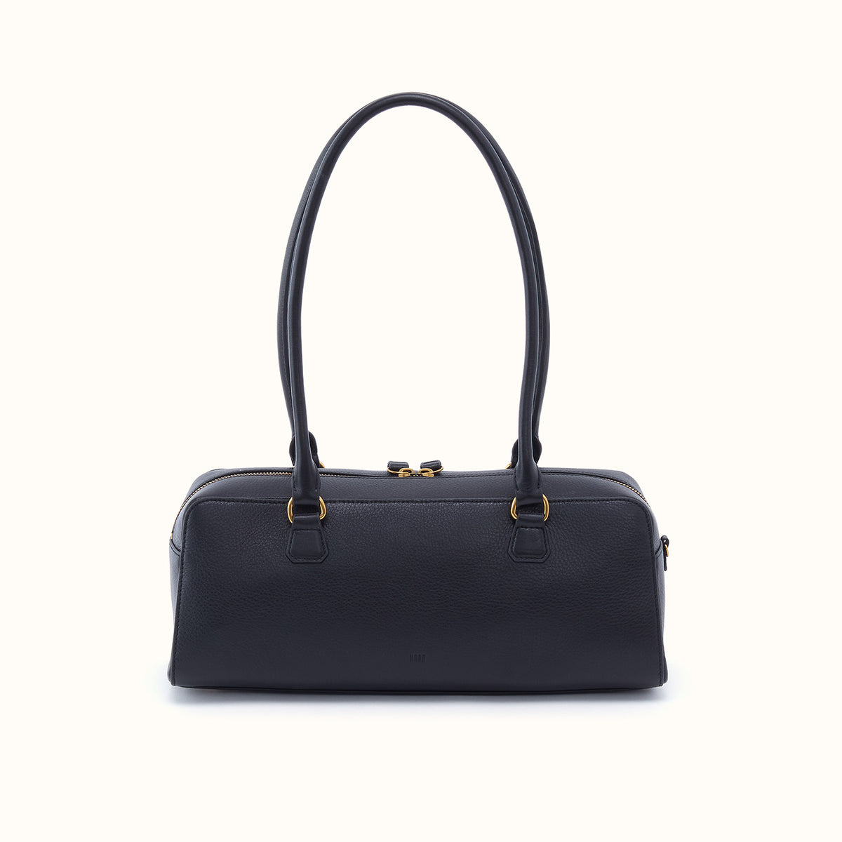 A black leather handbag with double top handles and gold-tone hardware, photographed against a clean off-white background.